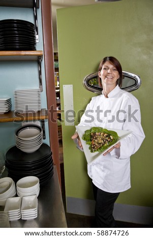 Chef working in restaurant standing at kitchen doorway with gourmet salad place