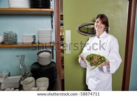 Chef working in restaurant standing at kitchen doorway with gourmet salad place