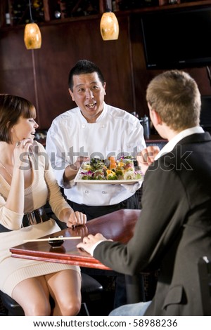 Japanese sushi chef serving platter of sushi to young couple