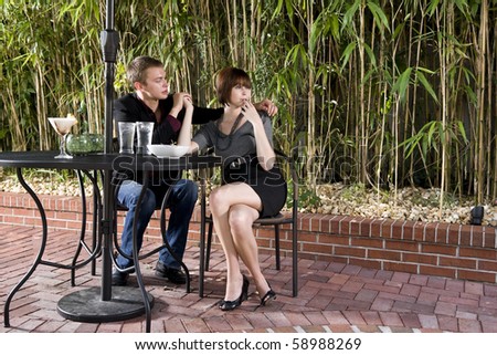 Young serious romantic couple holding hands dining on patio