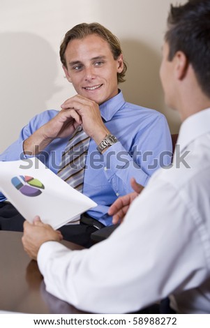 Two businessmen discussing financial results looking at pie chart