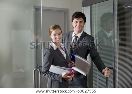 Two office workers in suits opening boardroom door