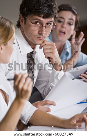 Businessman reviewing documents with female co-workers watching