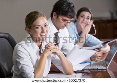 Female office worker with colleagues reading reports, focus on woman in foreground