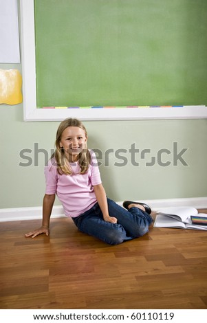 Back to school - girl in classroom by green blackboard, 8 years old