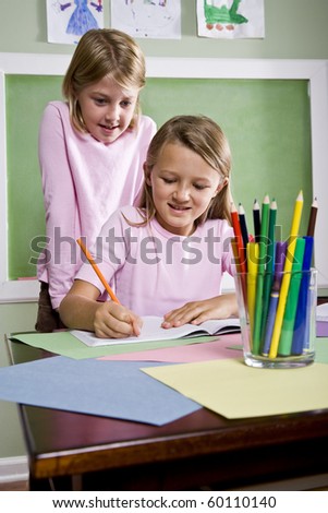 Back to school - 8 year old girls writing in notebook in classroom