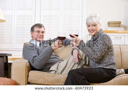 Senior couple relaxing together on couch with glass of red wine