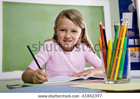Back to school - close-up of 8 year old girl writing in notebook in classroom