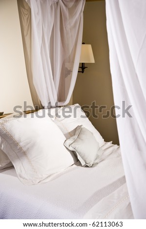 Pillows on a white canopy bed with curtains