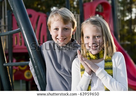 Boy (11 years) standing with sister (10 years) by playground equipment