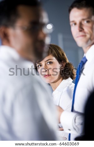 Face of businesswoman, 40s, looking out between two men standing beside