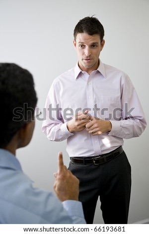 Male office worker, 30s, standing and listening to African American colleague talking