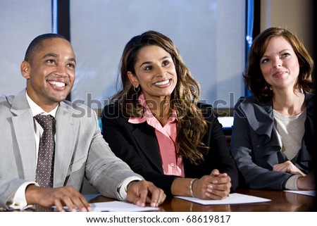 Multiethnic office workers in boardroom watching presentation, main focus on woman in middle
