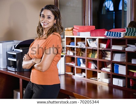 Female office worker, Indian ethnicity, standing in mailroom with office equipment