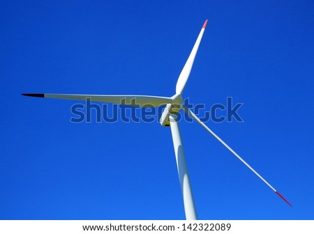 Red and white wind turbine by beautiful weather and deep blue sky