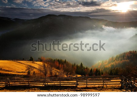 An awesome mountain landscape with sun, fog, and forrest