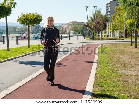 young girl jogging outdoor along trees path