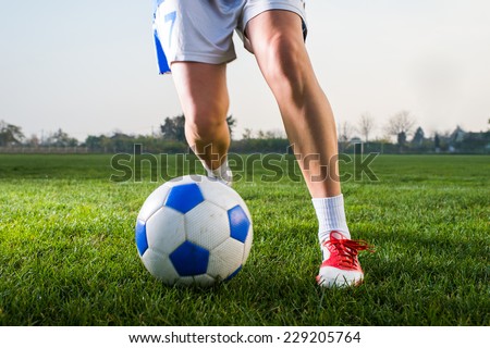 young girl kicking soccer ball on field