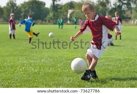 boy kicking football on the sports field