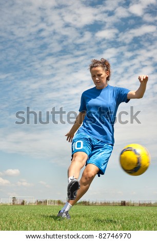 young girl kicking soccer ball on field