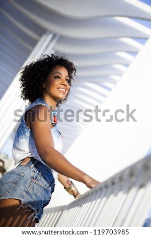 Portrait of a young black woman, fashion model wearing short jeans with afro hairstyle in urban background