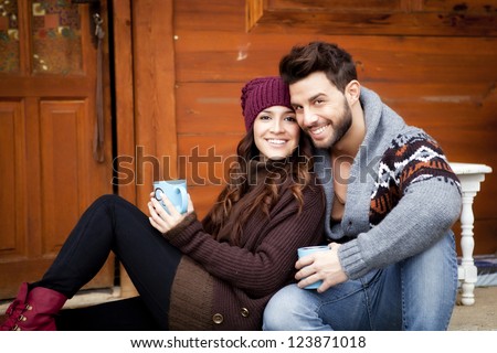 Young Couple Having Breakfast In A Romantic Cabin Outdoors In Winter.