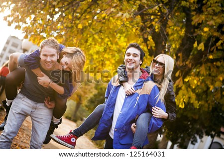 Groups of friends in the park. Guys are piggybacking the girls.