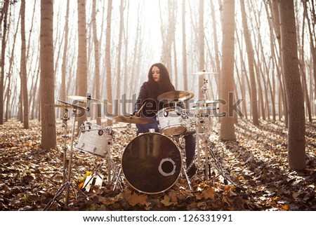 Young woman playing drums outdoors (Focus on the drum)