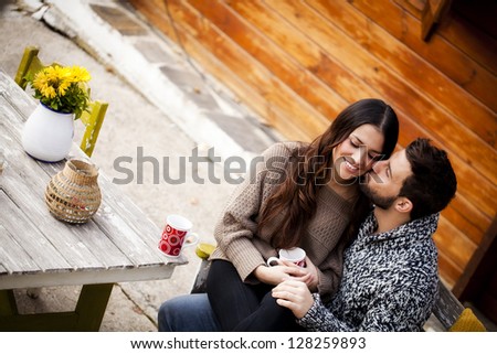 Young couple having breakfast in a romantic cabin outdoors in winter. He is kissing her cheek