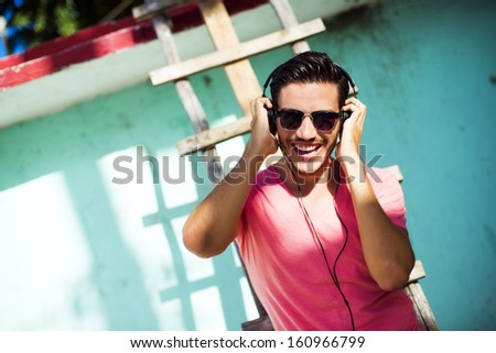 Young Man With Headphones Listening Music On A Urban Background