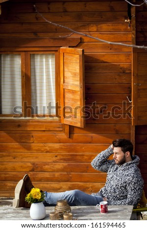 Young man having breakfast in a cabin outdoors in winter.