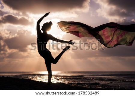 Silhouette of a young woman dancing at the beach with a tissue