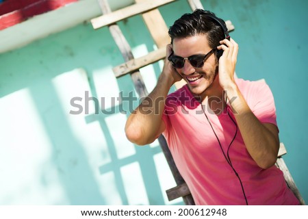 Young man with headphones listening music on a urban background