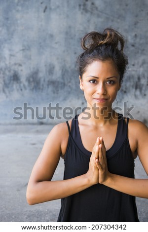 Latin woman practicing meditation against a urban background