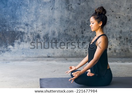 Latin woman practicing meditation against a urban background