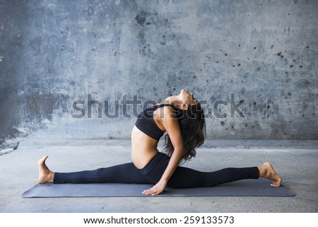 Woman practicing yoga against a brick wall