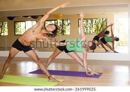Male and female practicing yoga in an indoor studio