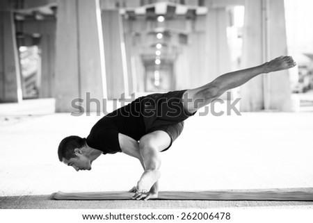 Man practicing advanced yoga in a urban background