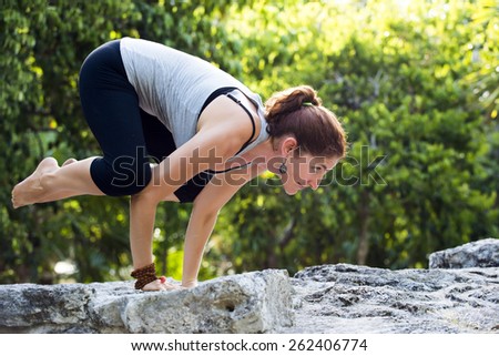 Woman practicing yoga outdoors - crow pose
