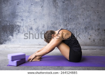 Woman sitting on her mat hiding her face between her legs. Finding refuge in yoga practice.