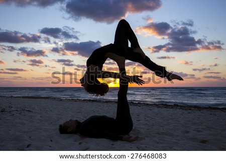 Couple practicing acroyoga at sunrise