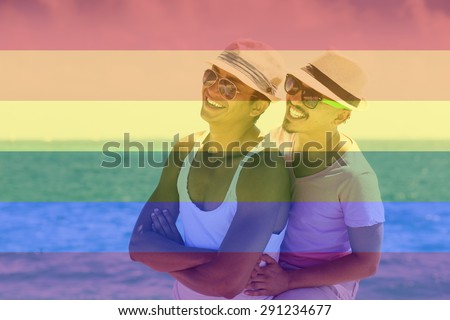 Celebrating marriage equality, couple in the Caribbean, laughing, hugging, looking to a side with the LGBT flag overlapped with medium opacity. . Isla Mujeres, Cancun, Mexico