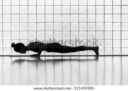 Young woman practicing in a yoga studio. Plank pose during sun salutations.