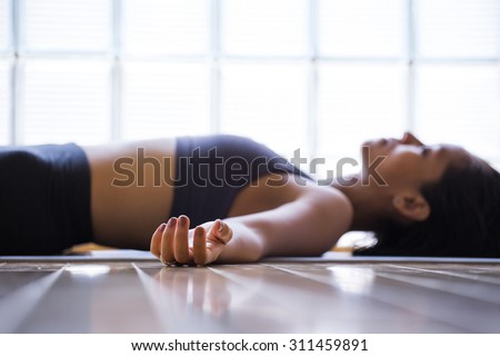 Young woman practicing in a yoga studio. Shavasana or corps pose is the end of a class or practice.