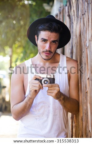 Handsome hipster photographer with a vintage film camera shooting outdoors