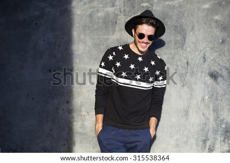 Young man posing with a trendy outfit against a urban background