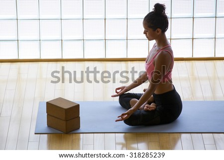 Young woman practicing meditation in a yoga studio indoors.
