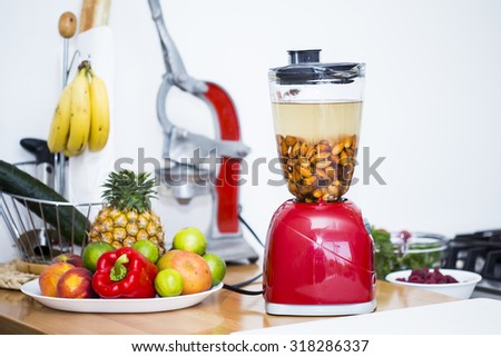 Blender with soaked almonds, to make milk at home in a beautiful kitchen counter full of fresh fruits. A vegan healthy option.