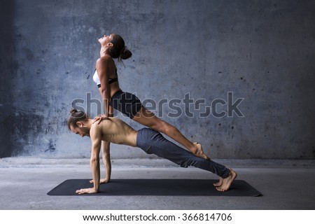 Couple practicing yoga together, upward facing dog on top of plank pose
