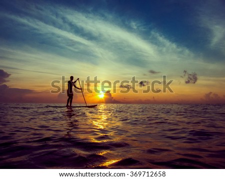 Young man paddle boarding during a beautiful sunrise in Mexico